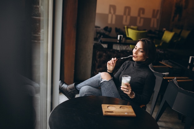 Woman drinking coffee in a cafe and looking through the window