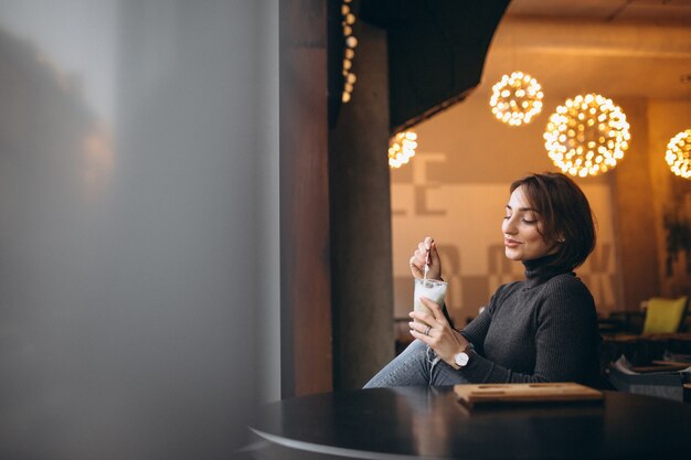 Photo woman drinking coffee in a cafe and looking through the window