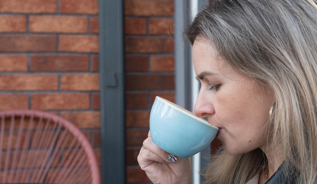 屋外のカフェでコーヒーを飲む女性