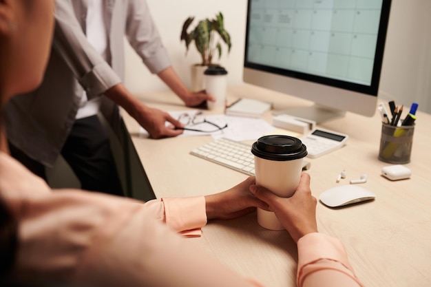 Photo woman drinking coffee in disposable cup when planing work with colleague at meeting