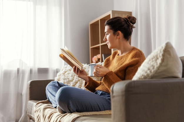 woman drinking coffee and reading book at home