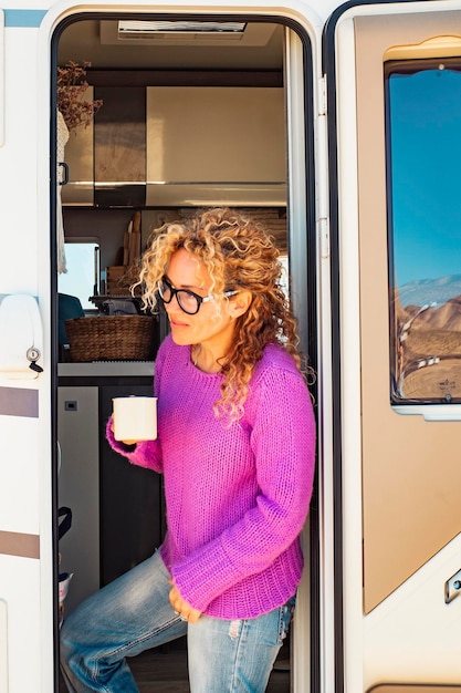 Photo woman drinking coffee sitting at the door of a camper van