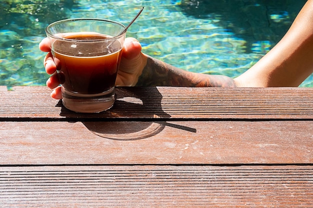 Женщина пьет кофе в бассейне Утренний кофе у бассейна