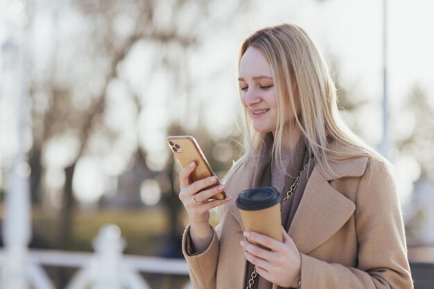 woman drinking coffee takeaway and using smartphone