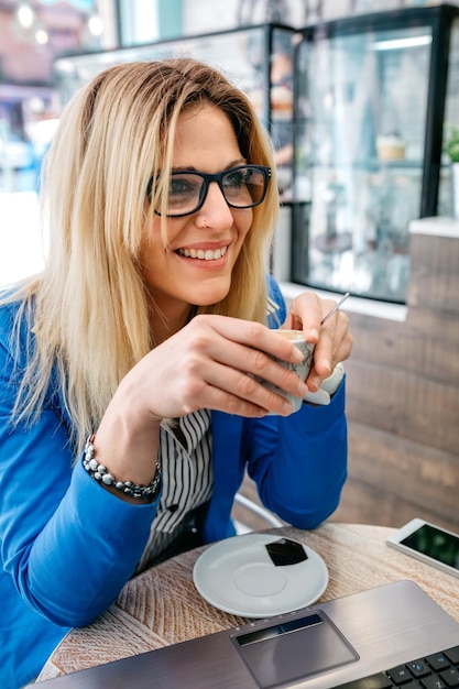 コーヒーを飲み、喫茶店でノートパソコンを使用している女性