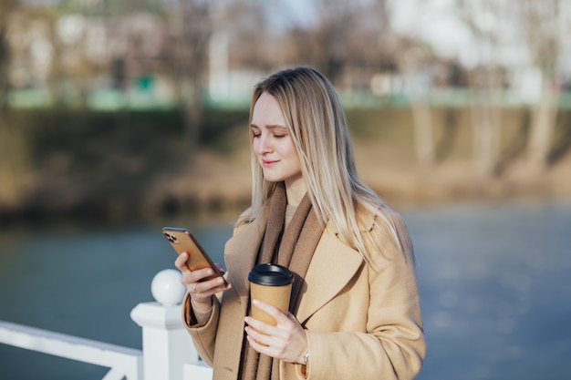 コーヒーを飲み、スマートフォンを使用している女性