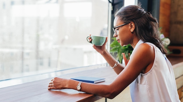 テーブルで本を読みながらコーヒーを飲んでいる女性