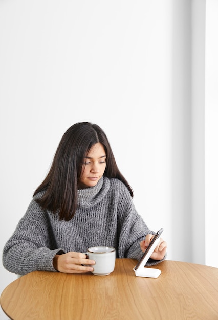 Woman drinking coffee while using phone