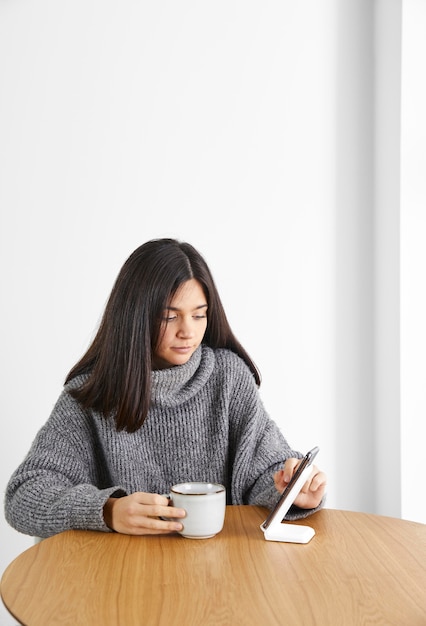 Foto donna che beve il caffè durante l'utilizzo del telefono