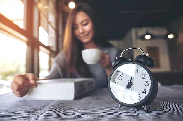 woman drinking coffee with alarm clock 