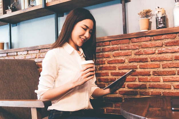 Woman drinking coffee and work on tablet at coffee shop