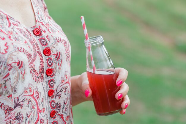 Woman drinking fruit shake from glass at park