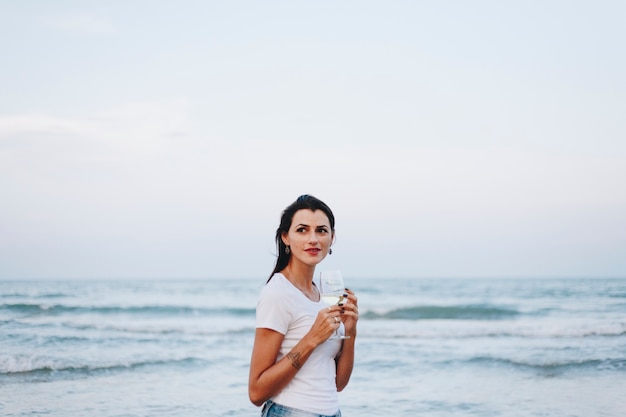 Donna che beve un bicchiere di vino sulla spiaggia