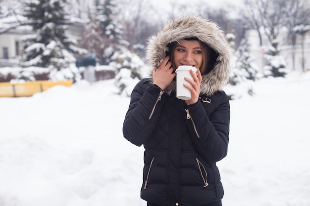 冬のカップから彼女の熱い飲み物のお茶やコーヒーを飲む女性