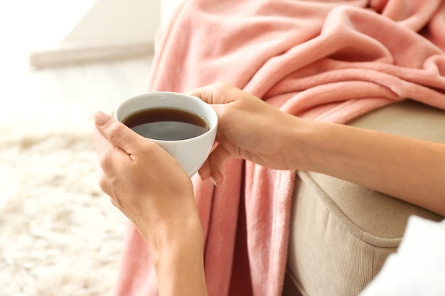 Woman drinking hot tea at home, closeup