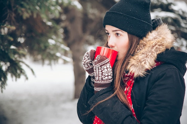 Woman drinking hot tea in the winter forest