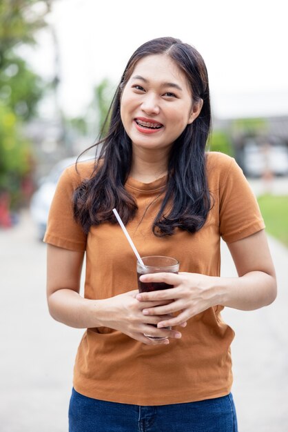 グラスでアイスコーラを飲む女性。コーラのグラス、氷とソフトドリンク、食べ物や飲み物のコンセプト。