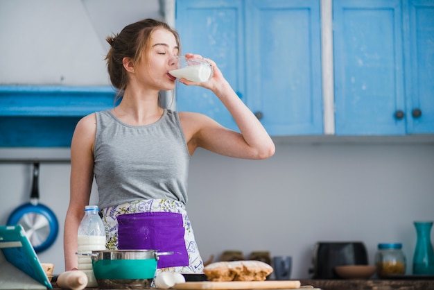 Donna che beve latte in cucina