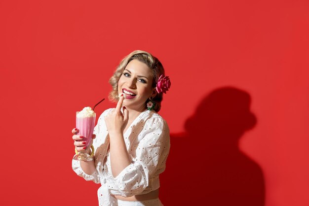 Woman drinking a milkshake against a red background Retro style woman portrait