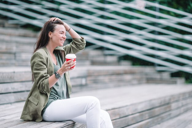 公園で屋外でおいしいコーヒーを飲む女性