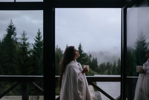 Woman drinking tea on cozy balcony of a country house