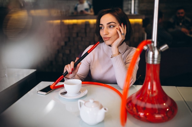 Woman drinking tea and smoking shisha