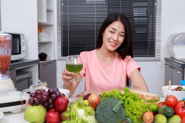 Donna che beve succo di verdura in cucina