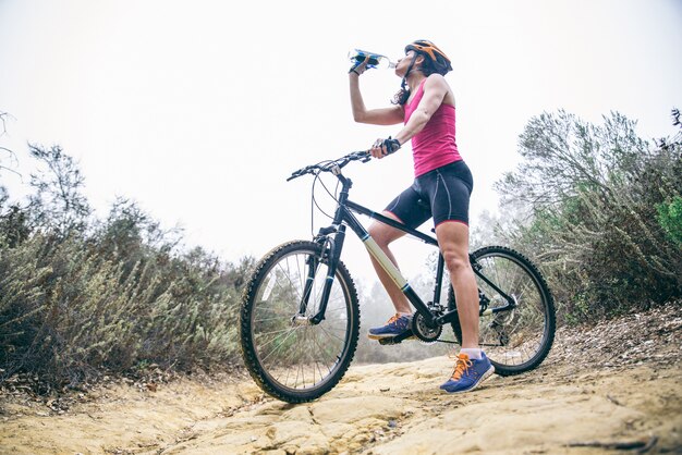 自転車で水を飲む女性