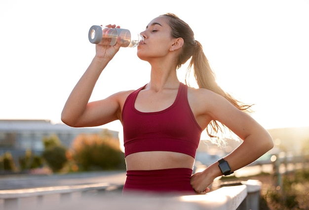 Woman drinking water and break in city for fitness catching breath and electrolytes for wellness Runner bottle or fresh air in Italy for sports thirsty or tired in town and exhausted in training