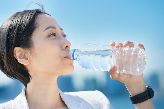 写真 ペットボトルから水を飲む女性
