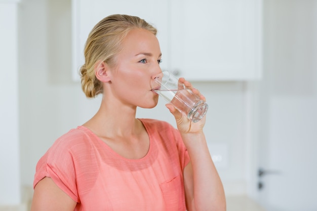 キッチンのガラスから水を飲む女性