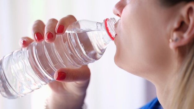 Woman drinking water from plastic bottle closeup