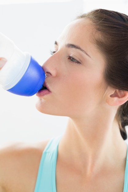 Woman drinking water at the gym after working out 