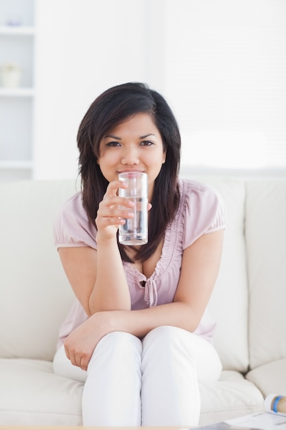 Woman drinking water while sitting in a couch