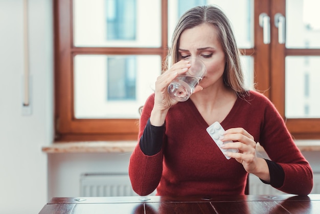 写真 薬を飲みながら水を飲む女性