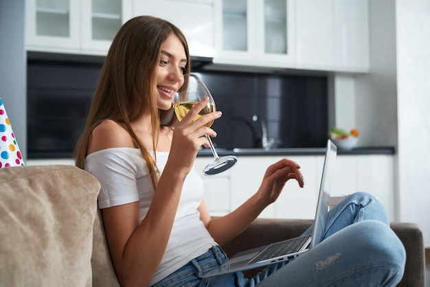 Woman drinking white wine and talking during video call