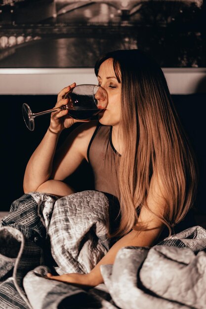 写真 家に座ってワインを飲んでいる女性