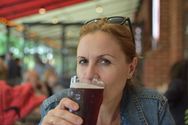 A woman drinks a beer in a small restaurant