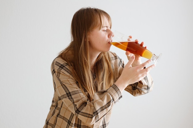 女性は白い背景のアルコール依存症でビールを飲みます