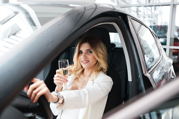женщина пьет шампанское в машине