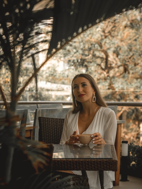 Woman drinks coffee in cafe. Beige blogging edit