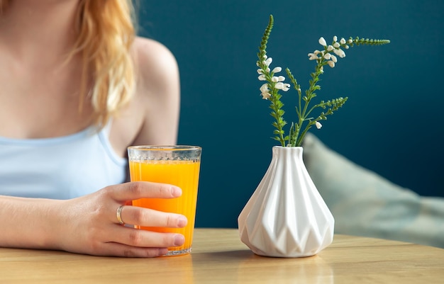 Woman drinks orange juice in a cafe closeup