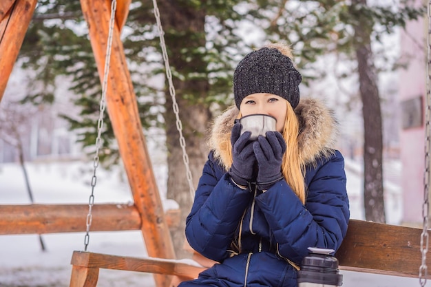 Woman drinks tea from a thermos on a winter day