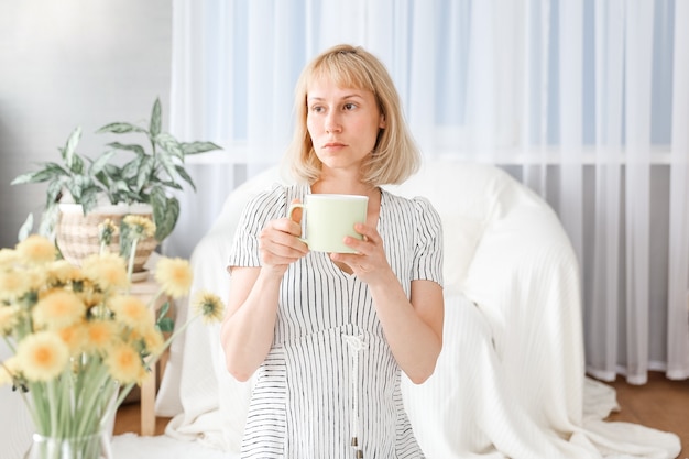 A woman drinks tea in the living room