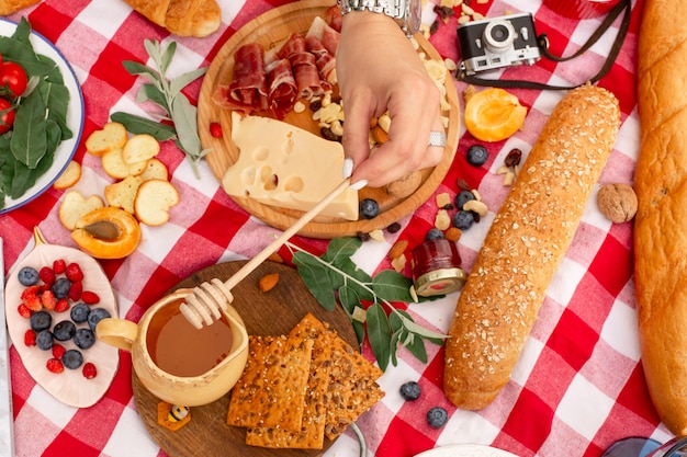 Woman drip honey on sandwich with parma and cheese at outdoor picnic