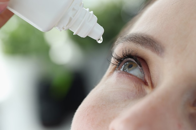 Фото Женщина капает ей в глаза с антибактериальными каплями крупным планом для лечения вирусного конъюнктивита