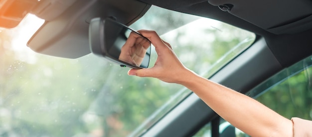 백미러를 조정하는 여성 운전자 자동차 여행 및 안전 교통 개념
