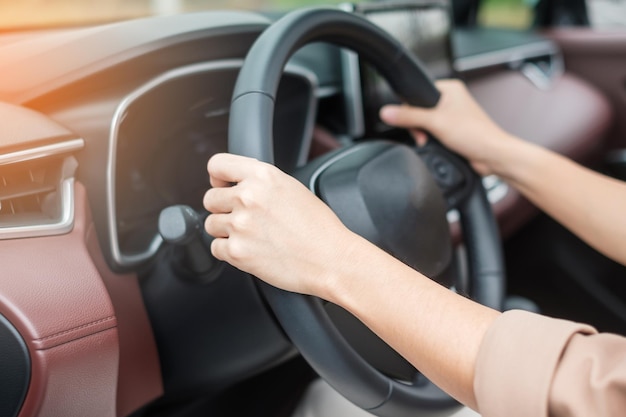 Женщина-водитель за рулем автомобиля на дороге, управляя рулем в современном электрическом автомобиле Путешествие и безопасность Транспортные концепции