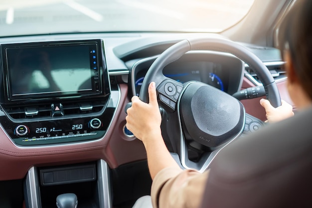 現代の電気自動車のステアリングホイールを制御する道路の手で車を運転する女性ドライバー旅と安全輸送の概念