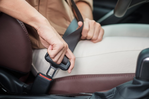 Cintura di sicurezza di fissaggio della mano del conducente della donna durante la seduta all'interno di un'auto e la guida nel concetto di viaggio e trasporto di sicurezza stradale